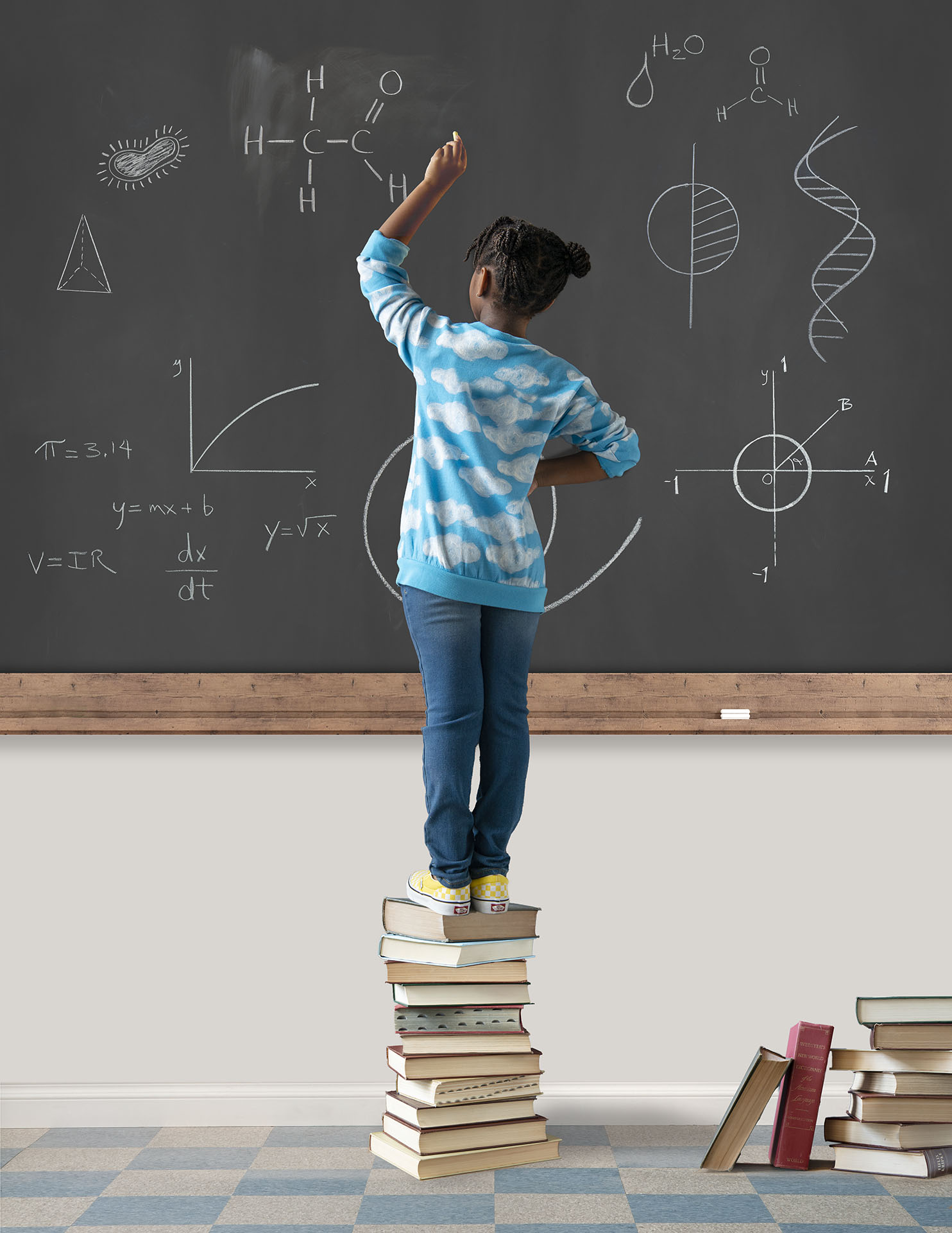 chid standing on books to be able to reach the blackboard