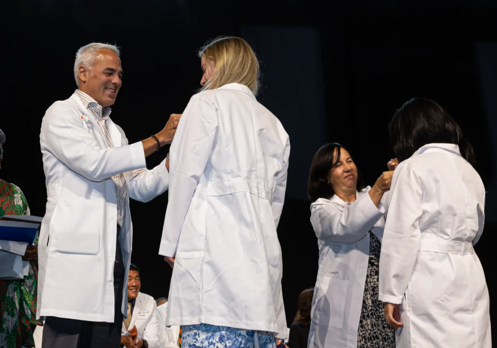 Javier Flores, M.D. ’95, and Pilar Gutierrez, M.D. ’90, pin two members of the Class of 2027 Javier Flores, M.D. ’95, and Pilar Gutierrez, M.D. ’90, pin two members of the Class of 2027